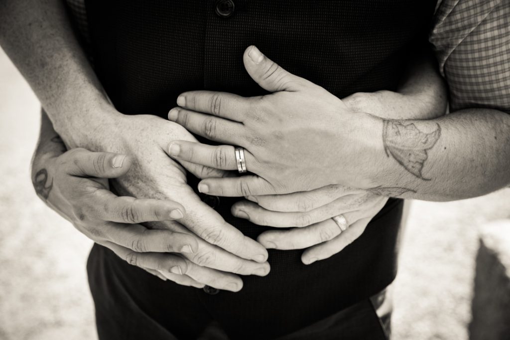Black and white photo of hands of two grooms