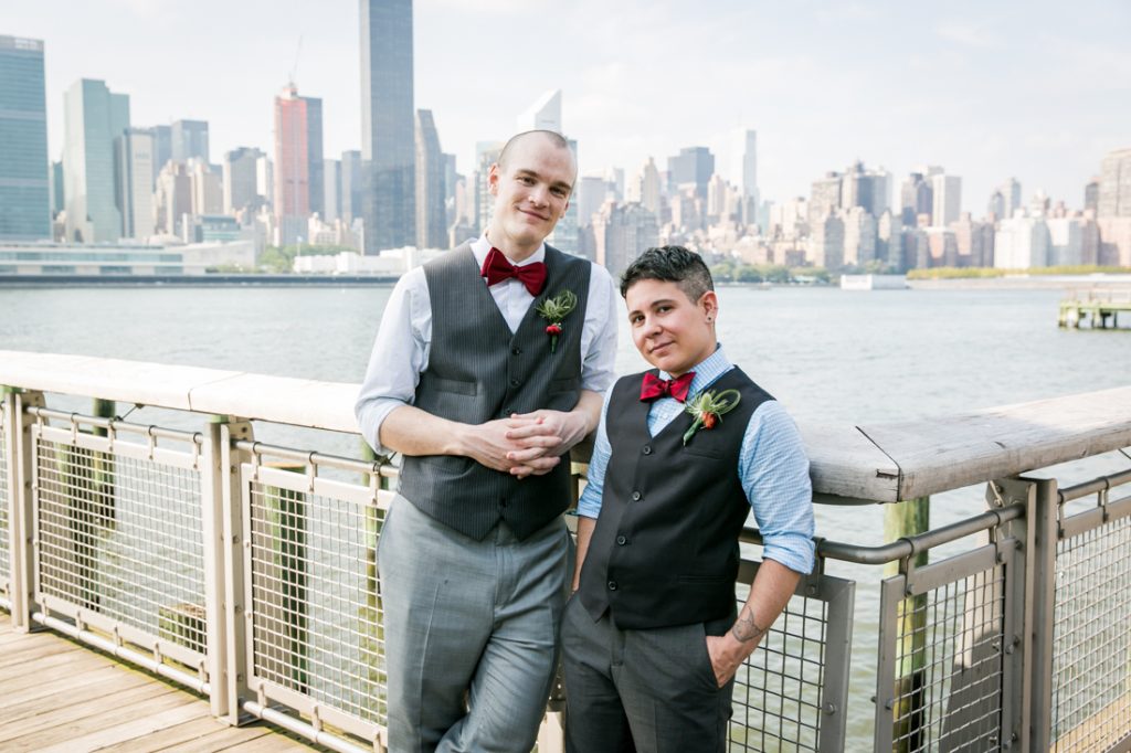 Two grooms wearing bow ties leaning against Gantry Plaza State Park railing