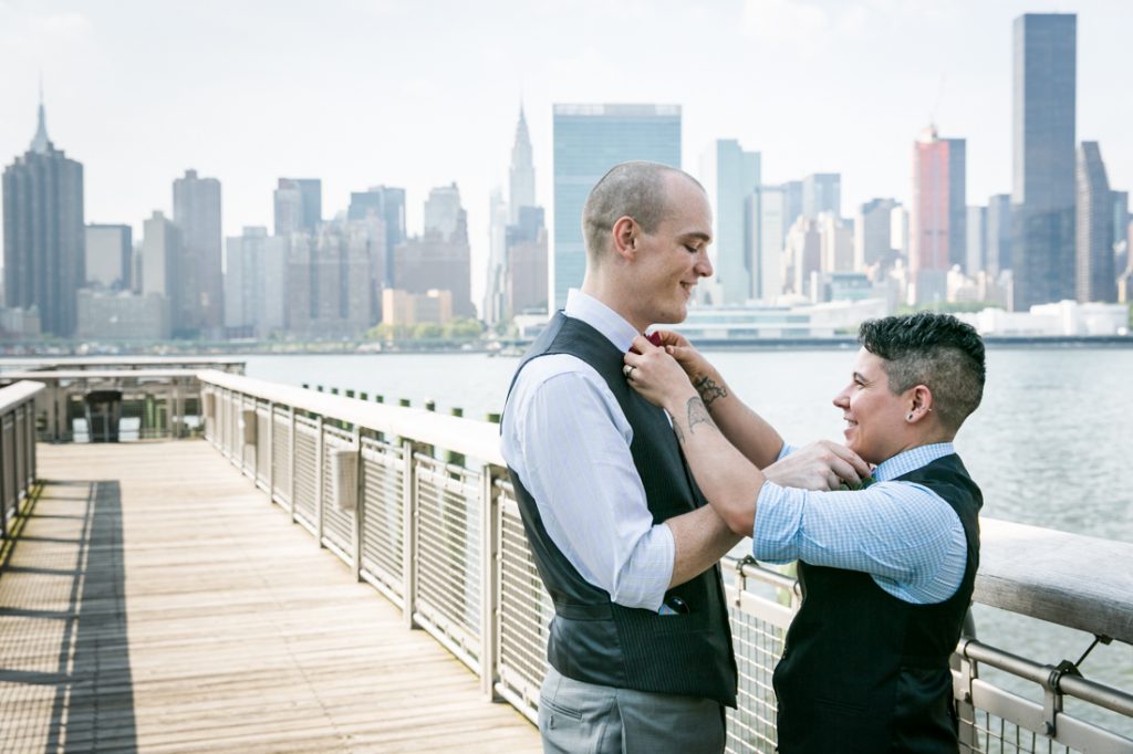Two grooms adjusting each other's bow ties at Gantry Plaza State Park