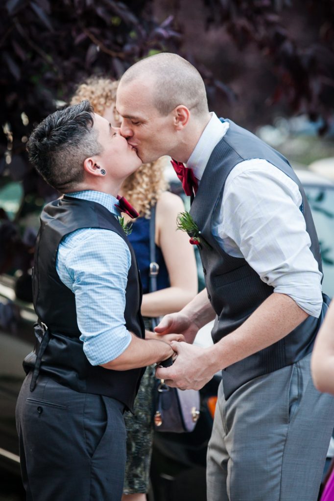 Two grooms kissing outside before at Astoria wedding reception