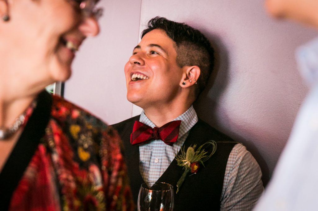 Groom laughing and listening during Astoria wedding reception
