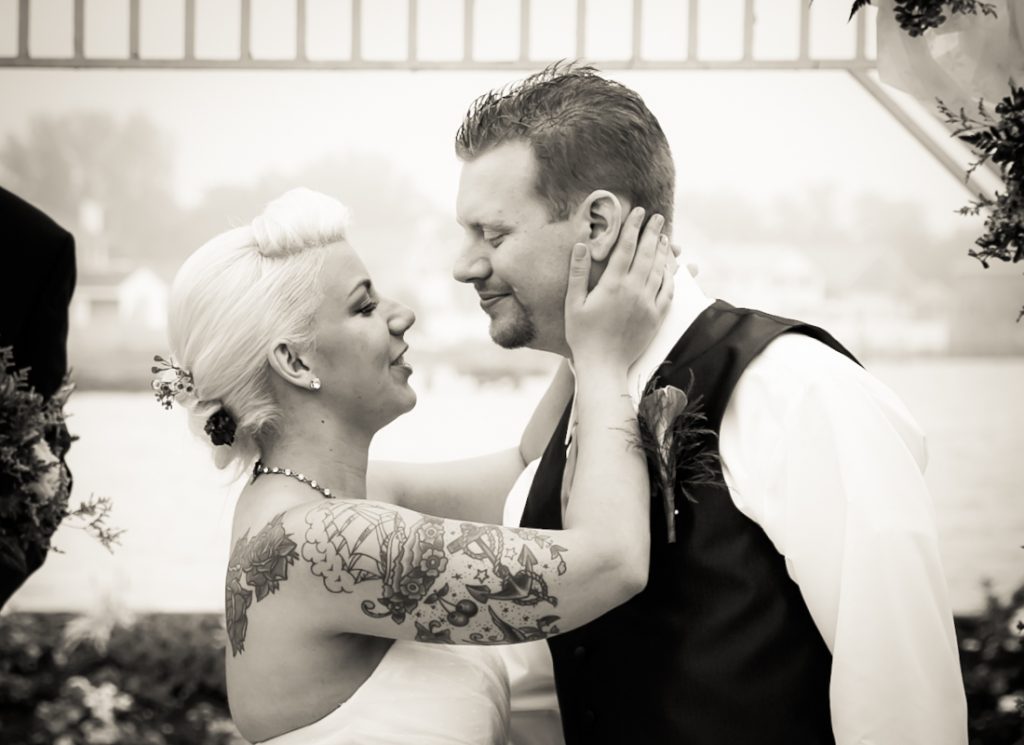 Black and white photo of bride touching groom's face during ceremony