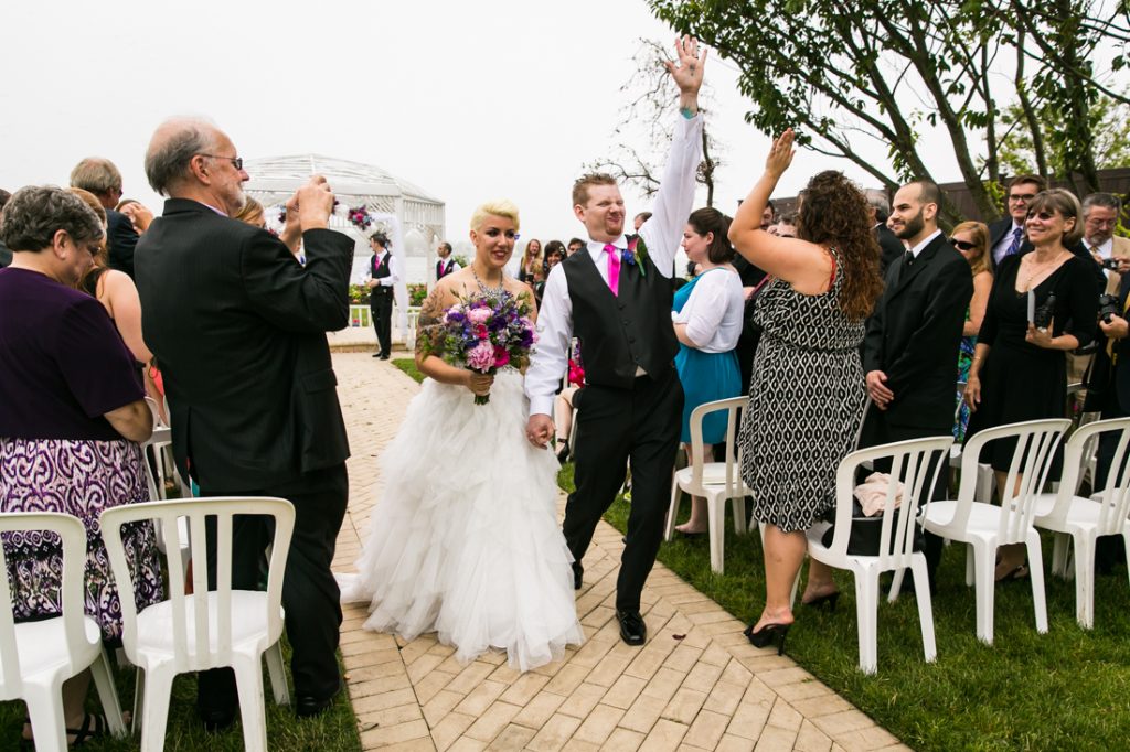 Groom pumping fist while walking with bride down aisle at Riviera Waterfront Mansion wedding