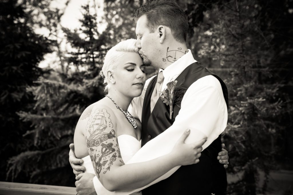 Black and white photo of groom kissing bride on forehead