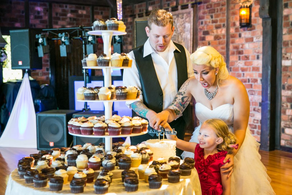 Bride, groom, and flower girl selecting cupcake at Riviera Waterfront Mansion wedding