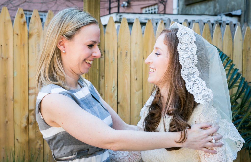 Maid of honor hugging bride at Brooklyn backyard wedding ceremony