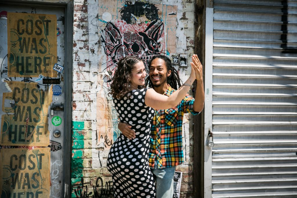 Meatpacking District engagement photos of couple dancing in front of graffiti wall