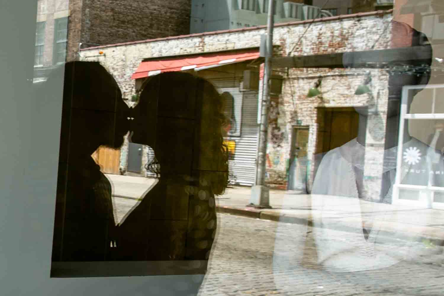 Reflection in window of couple kissing