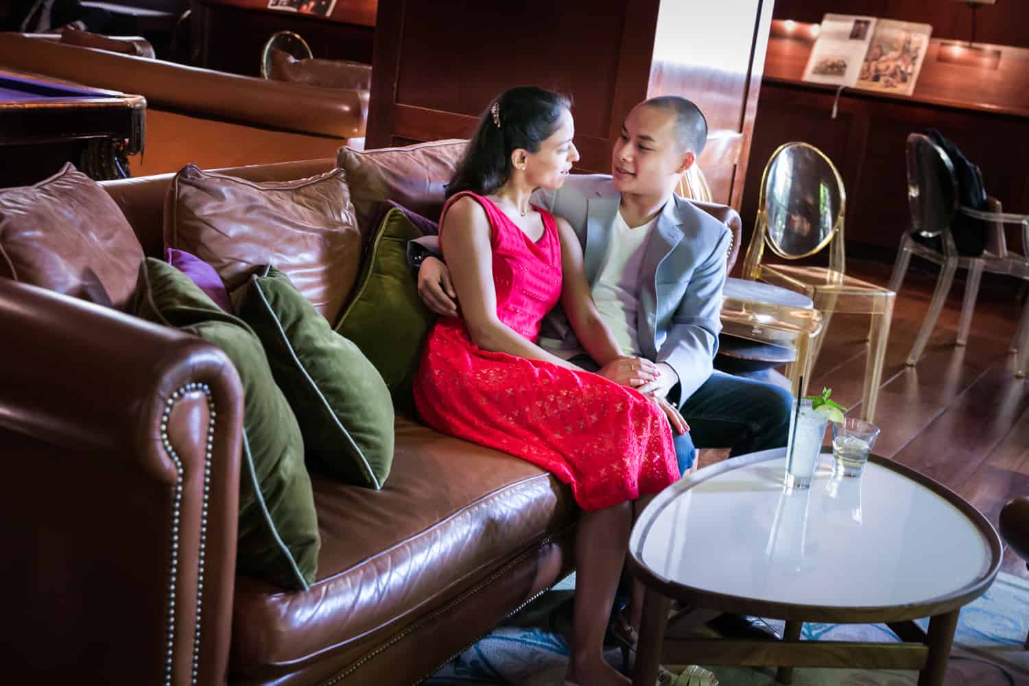 Couple sitting on couch at bar during a Hudson Hotel engagement shoot