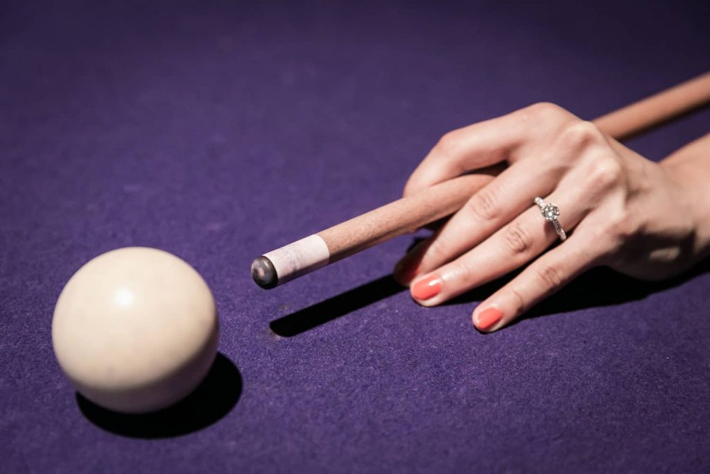 Close up on woman's hand about to hit cue ball during a Hudson Hotel engagement shoot