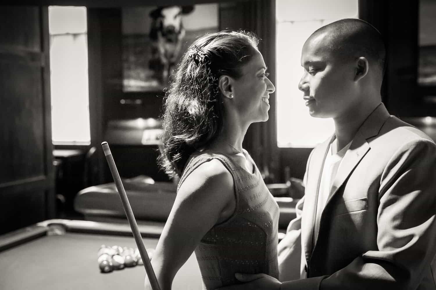 Black and white photo of couple leaning on pool table during a Hudson Hotel engagement shoot