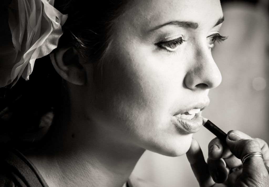 Black and white photo of lipstick being applied to bride