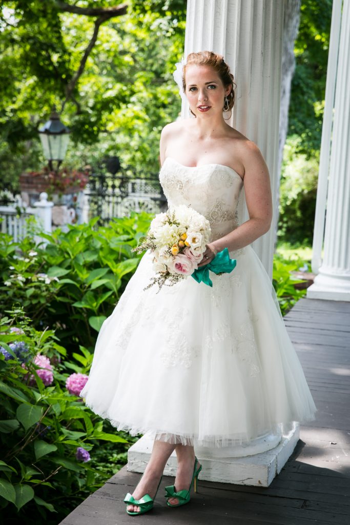 Bride with bouquet standing against column at a Round Hill House wedding