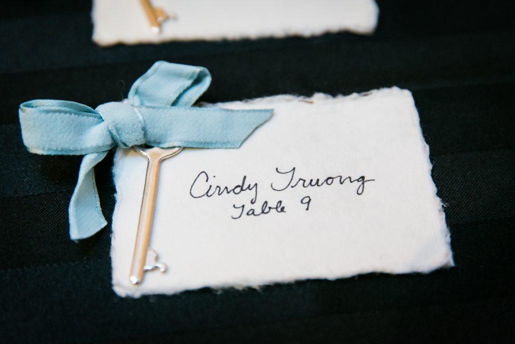Close up on guest escort card with key and blue ribbon
