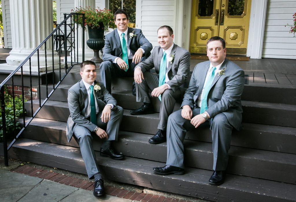 Groom and groomsmen sitting on steps at a Round Hill House wedding