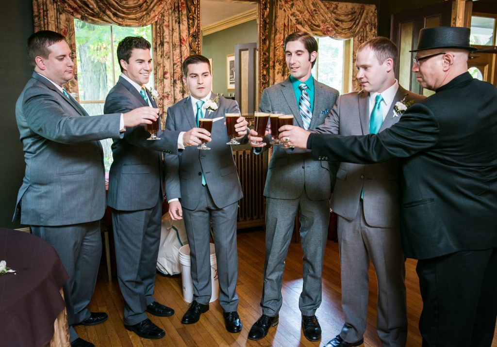 Groom and groomsmen cheering with glasses of beer
