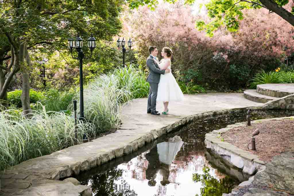 Bride and groom in garden standing by pond at a Round Hill House wedding