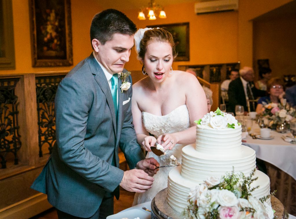 Bride and groom making faces while cutting cake