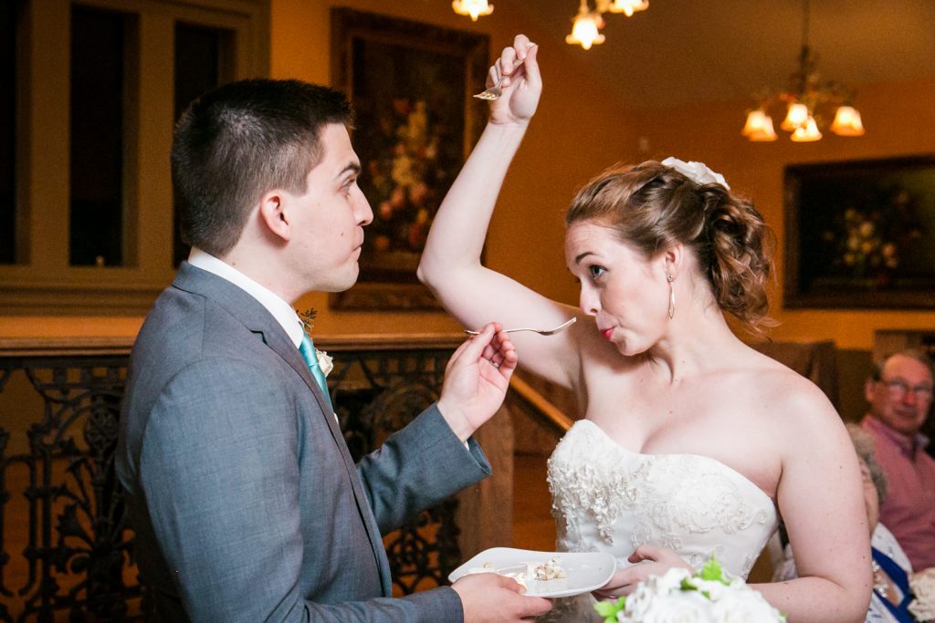 Bride dramatically feeding cake to groom at a Round Hill House wedding