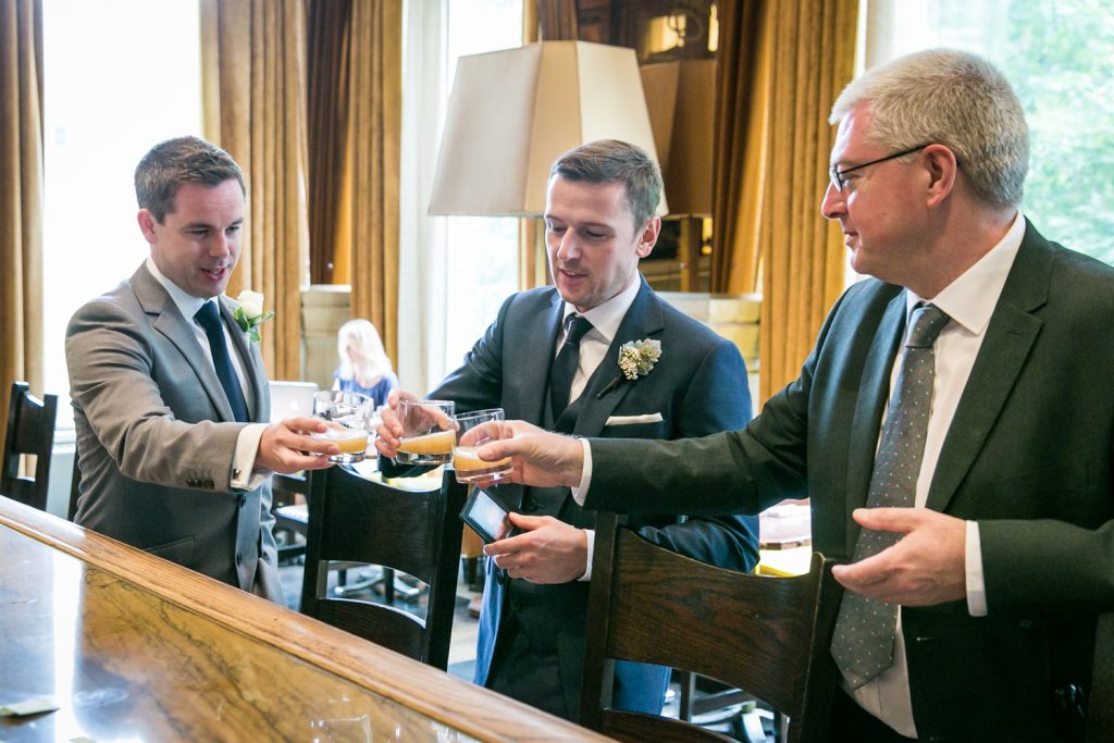Three men toasting glasses at the SoHo Grand Hotel bar