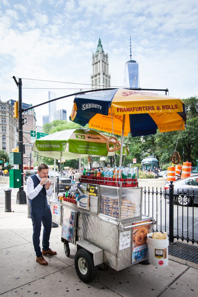 Groom eating in front of hot dog cart