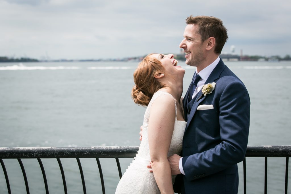 Bride and groom laughing in front of NYC waterfront