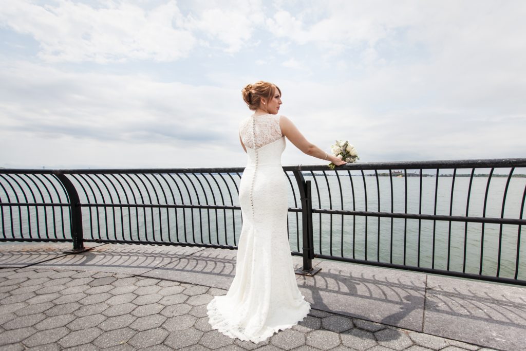 Bride looking over railing at NYC waterfront