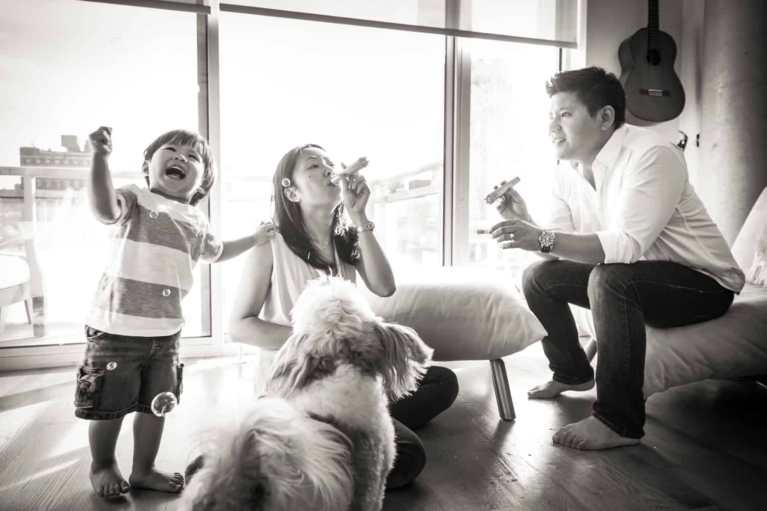 Black and white photo of parents and child blowing bubbles
