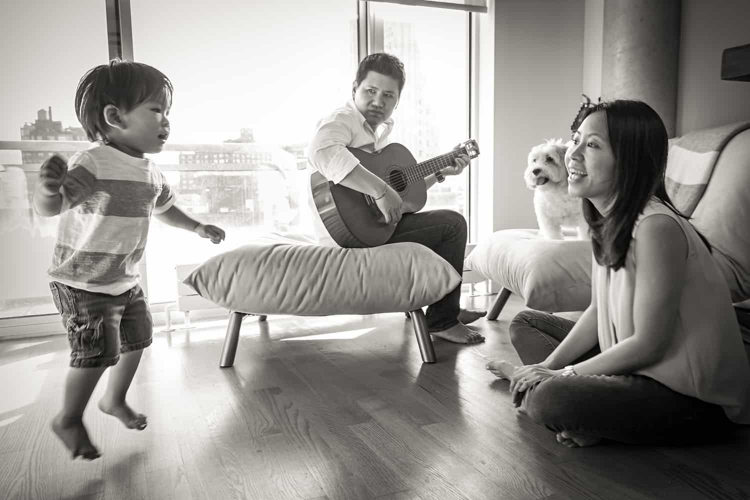 Black and white photo of parents and child playing a guitar