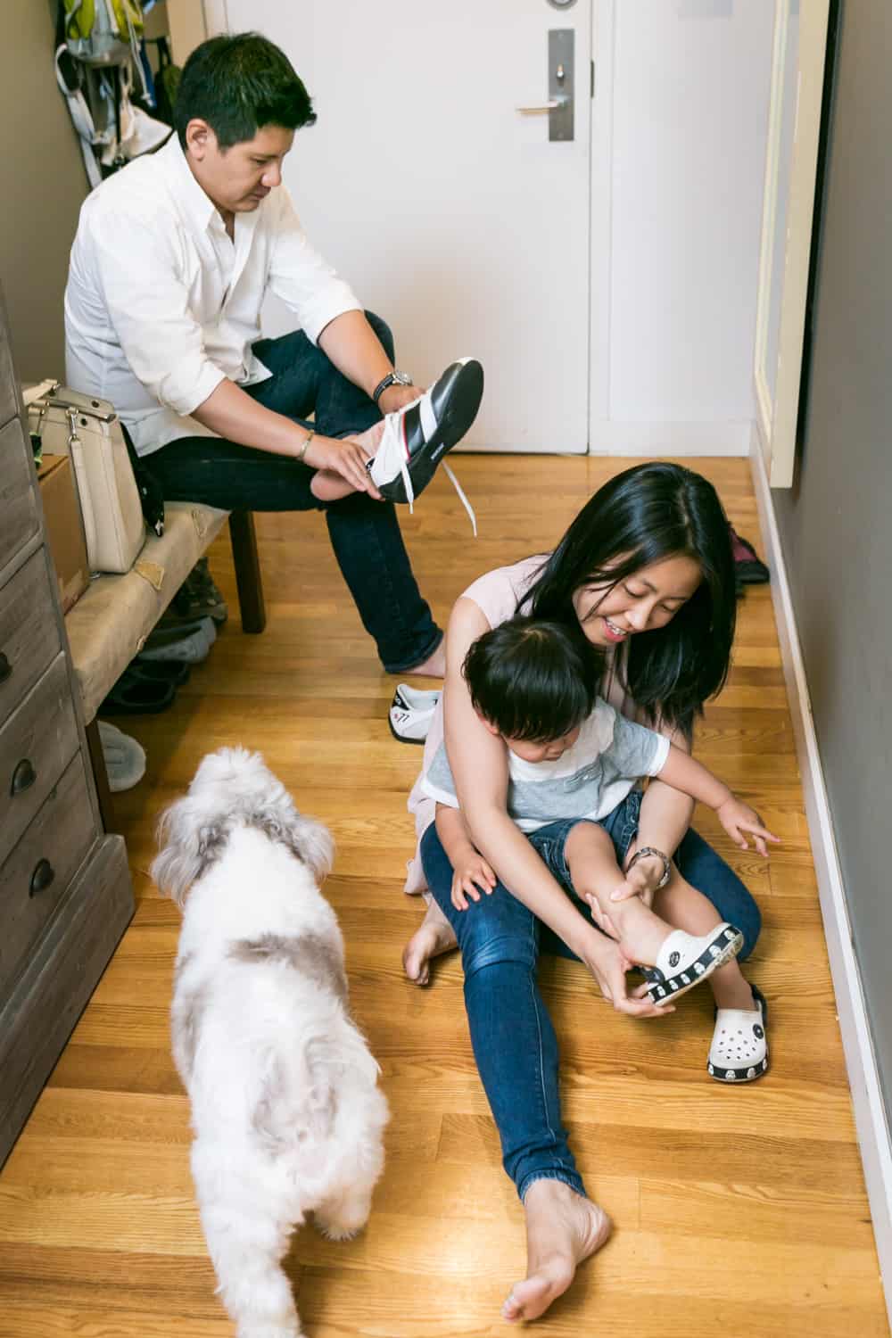 Asian American family putting on shoes in hallway