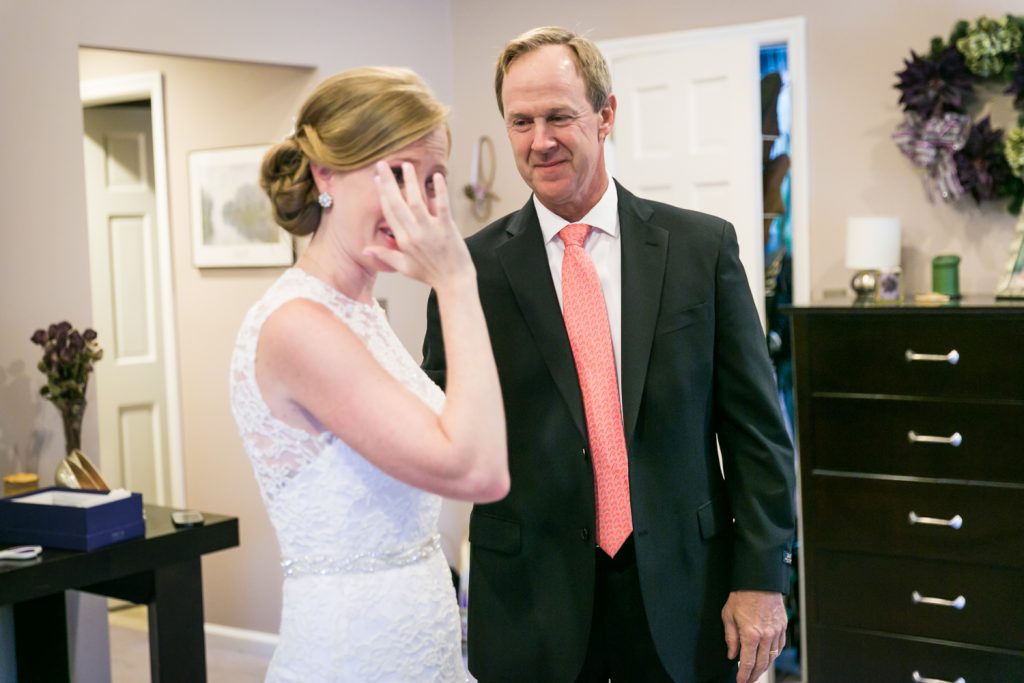 Bride wiping tears from her eye after first look with father