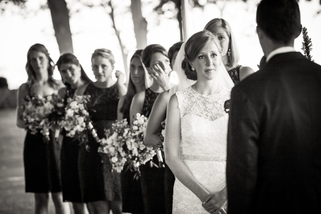 Black and white photo of bride watching groom during ceremony at an American Yacht Club wedding