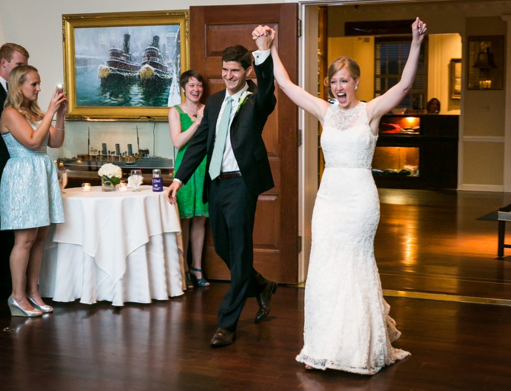Bride and groom entering reception with arms up at an American Yacht Club wedding