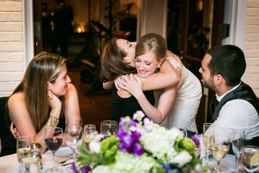 Bride hugging guest at table during reception