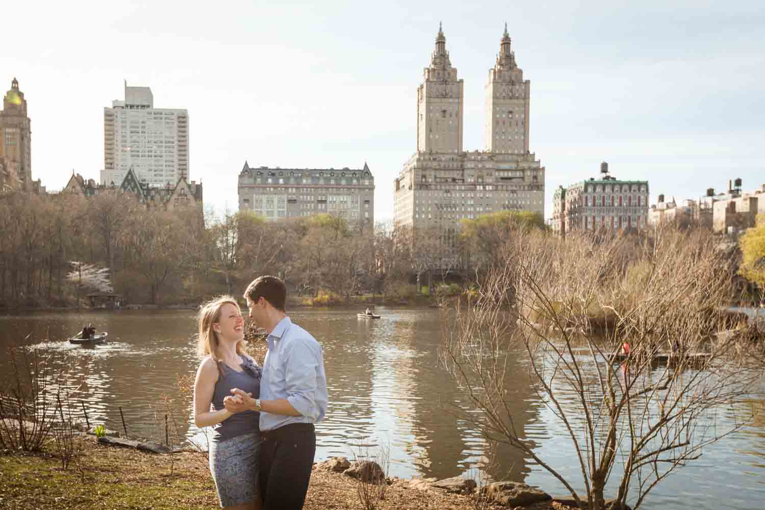 Man and woman dancing across from Central Park lake during a Central Park engagement session