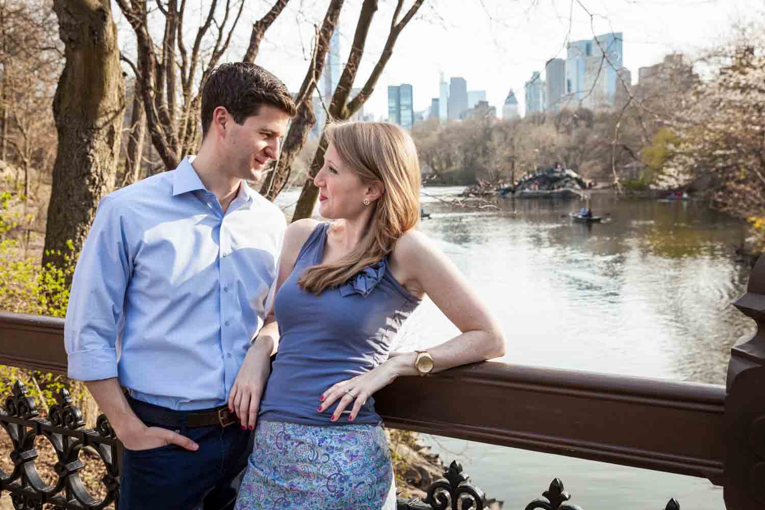 Man and woman looking at each other across from Central Park lake during a Central Park engagement session