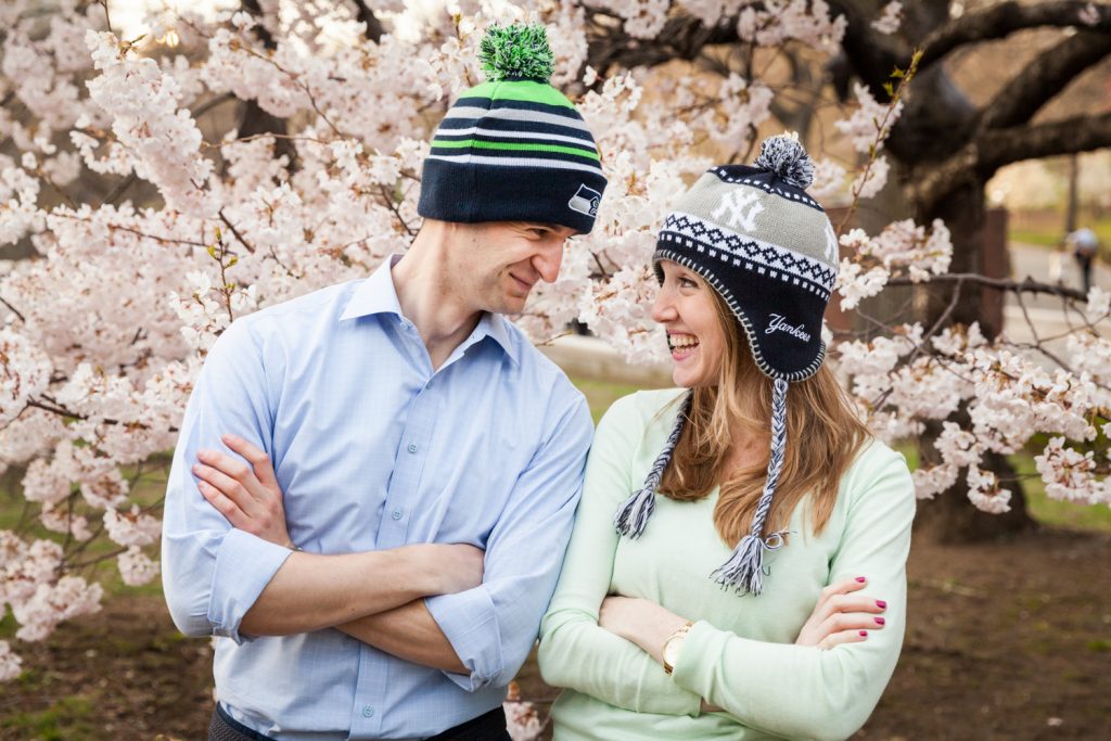 Couple wearing knit caps  in front of cherry blossom trees in Central Park