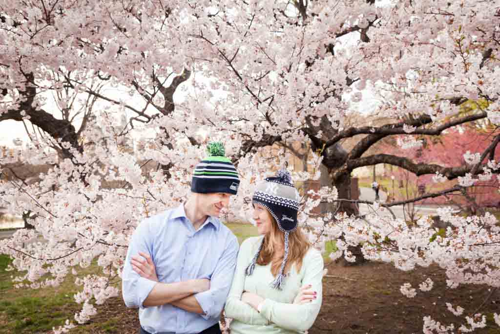 Couple wearing knit caps  in front of cherry blossom trees in Central Park