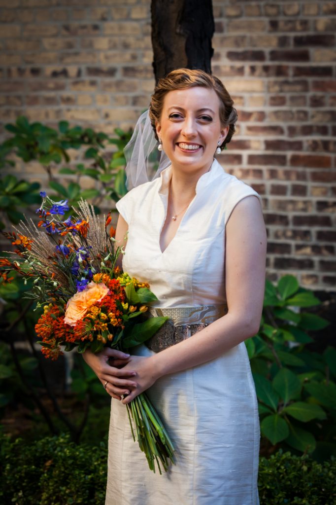 Portrait of bride wearing birdcage headpiece and holding flower bouquet