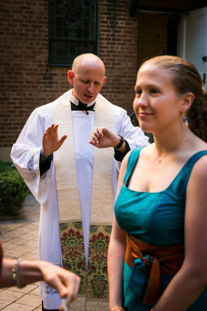 Priest looking at watch with bridesmaid