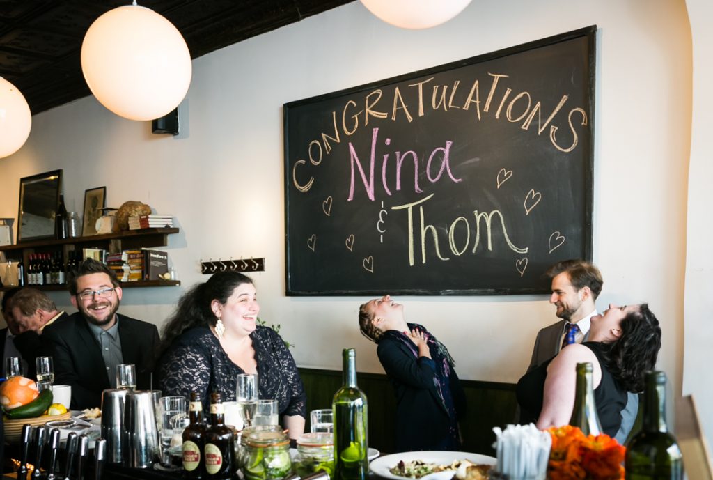 Guests laughing under chalkboard sign during Farm on Adderley wedding reception
