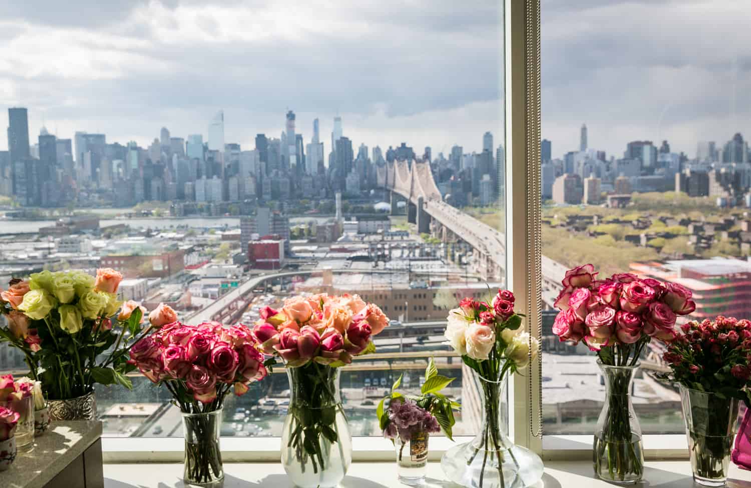 Vases of flowers on windowsill with NYC skyline in background