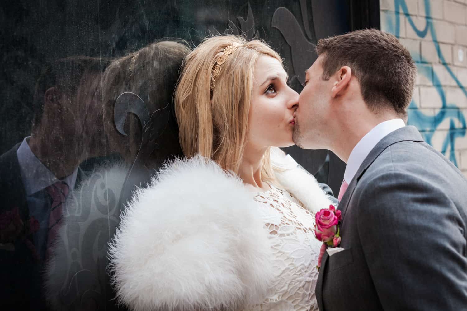 Bride and groom kissing against window