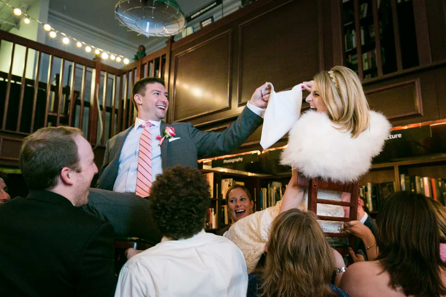 Bride and groom lifted up on chairs during hora dance at a Housing Works wedding