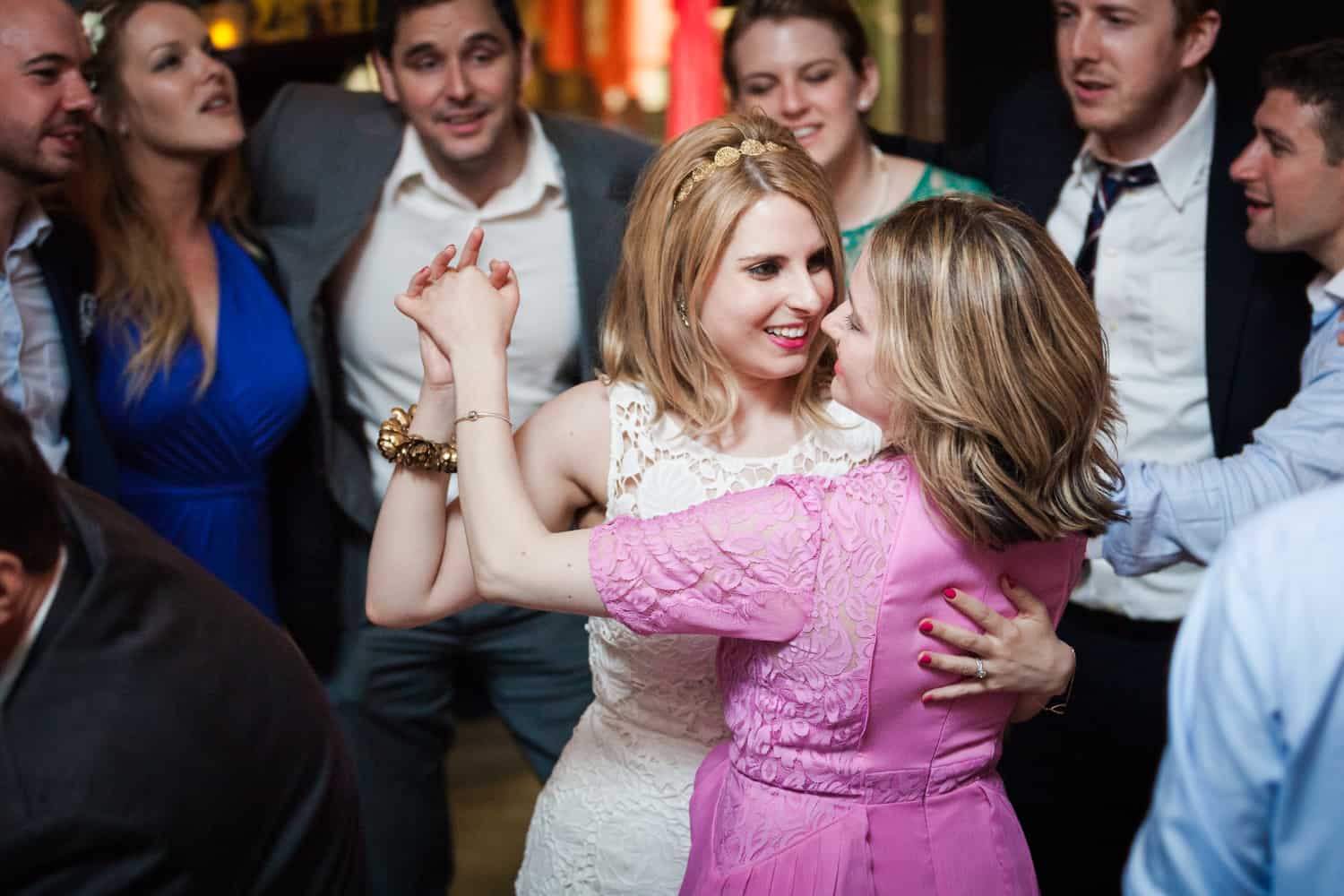 Bride and maid of honor dancing in front of guests