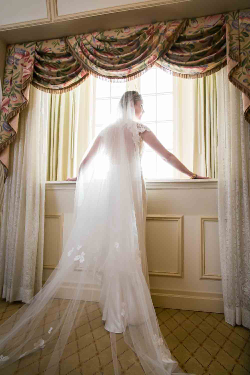 Bride wearing veil looking out window