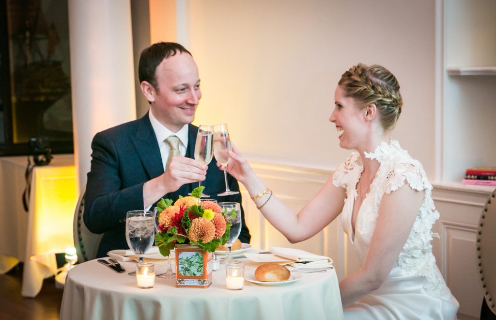 Bride and groom toasting champagne glasses at sweetheart table