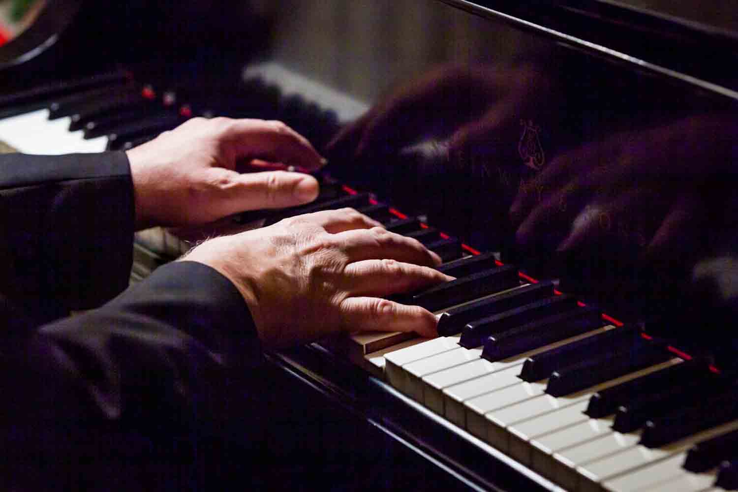 Close up on male hands playing the piano at a Lotos Club engagement party