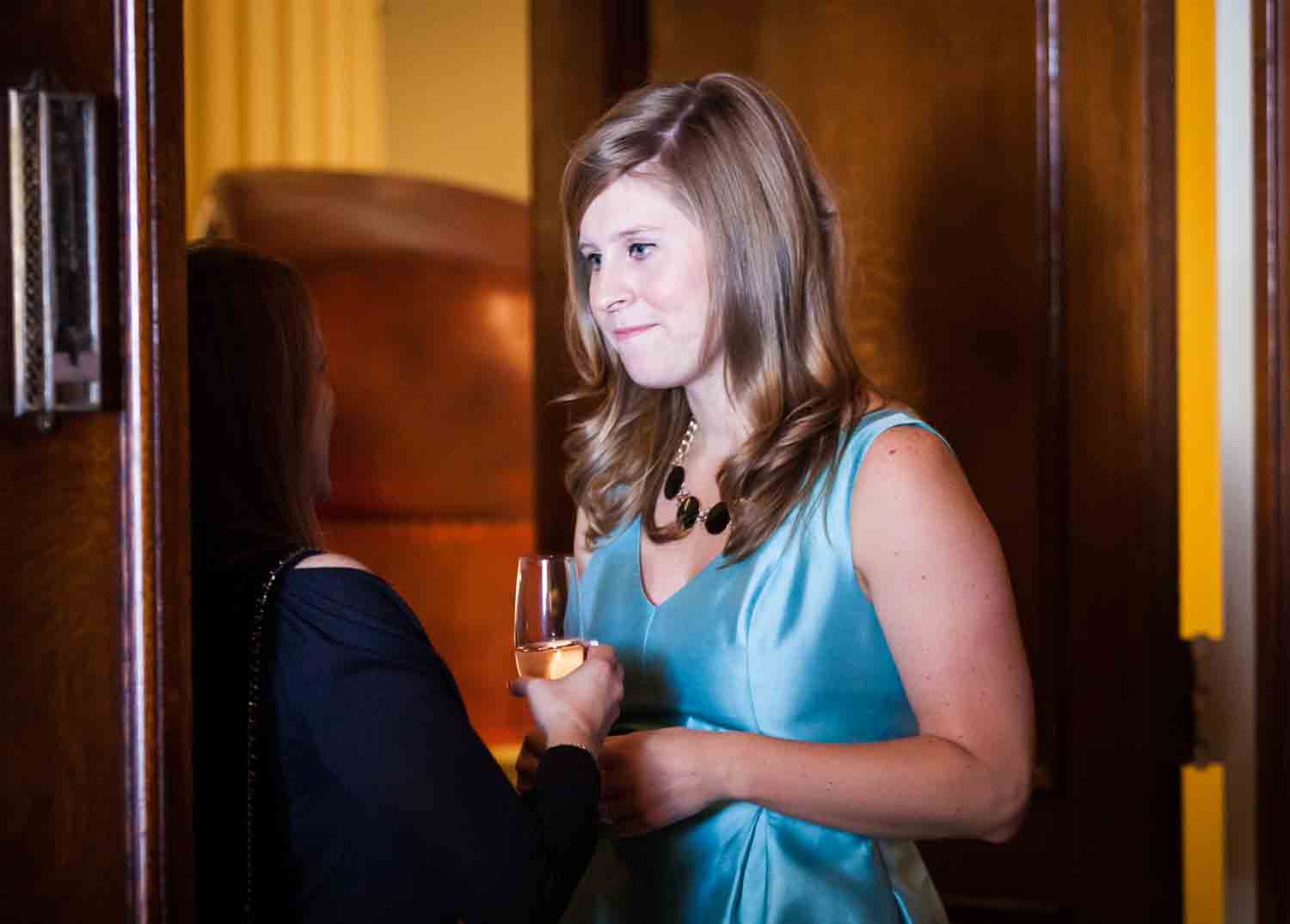 Woman in blue dress listening to guest at a Lotos Club engagement party