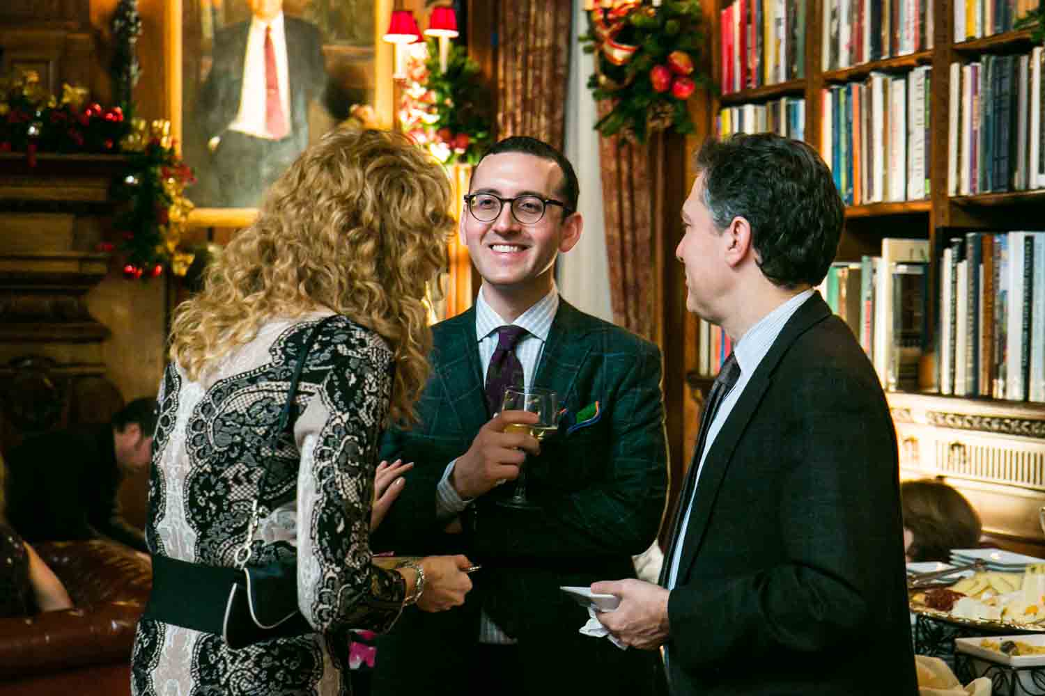 Groom and guests talking in library at a Lotos Club engagement party